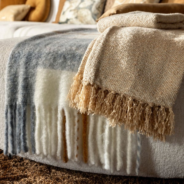 Dekorative Decken mit Fransen liegen auf einem Sofa.