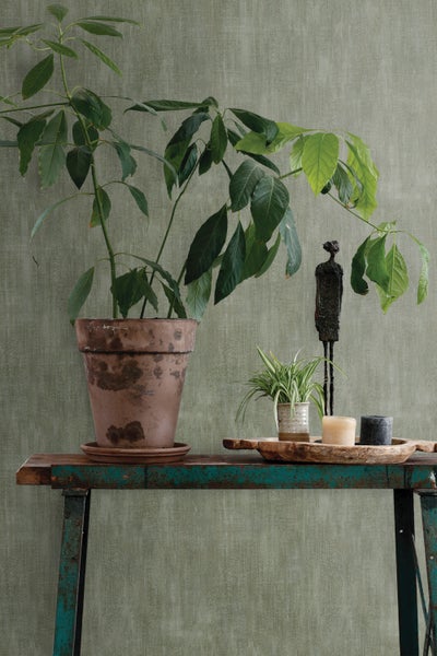 Dekorative Szene mit Zimmerpflanzen, Kerzen und einer Skulptur auf einem Tisch.