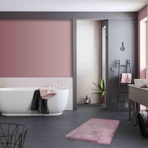 Helles Badezimmer mit Badewanne, Waschbecken und Textilien für ein gemütliches Ambiente.