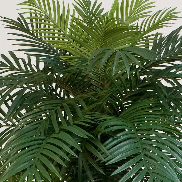 Künstliche Palme mit detailgetreuen Stämmen und grünen Palmwedeln.
