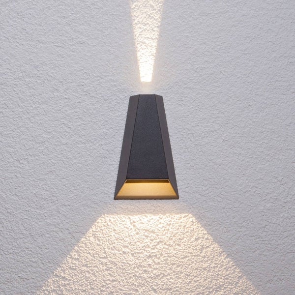 Trapezförmige Außenwandleuchte in Anthrazit mit Up- und Down-Lichtkegeln an einer Fassade.