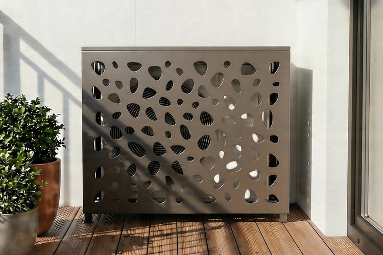 Moderne Klimaanlagen-Verkleidung aus Metall mit organischem Lochmuster auf einer Holzterrasse.