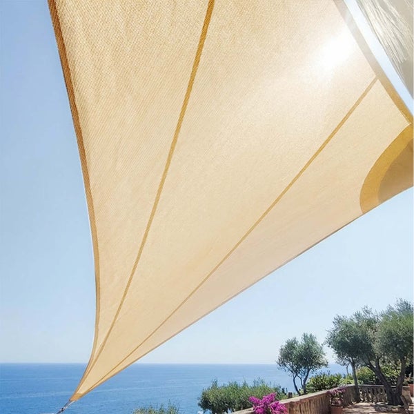 Sonnensegel in Beige über einer Terrasse mit Blick auf das Meer und blauen Himmel.