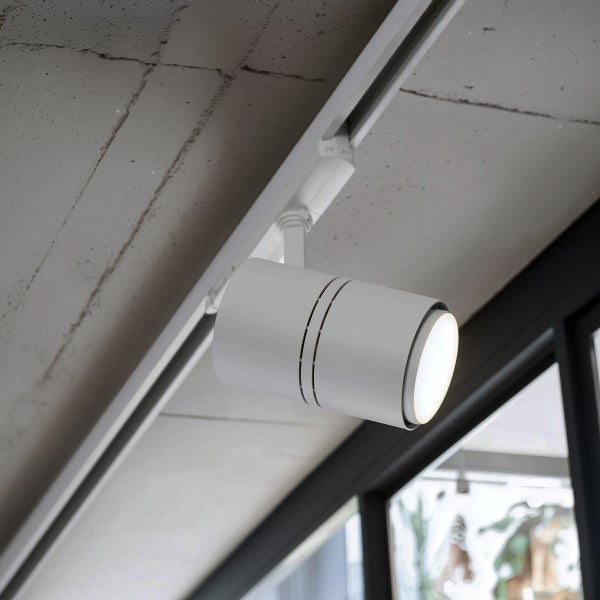 Zylindrischer Schienenspot in Weiß montiert an einer Deckenschiene an einer Betondecke.