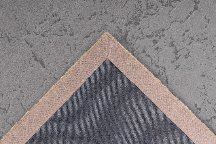 Nahaufnahme der Teppichrückseite mit gewebter Struktur und breiter Textileinfassung an der Ecke.