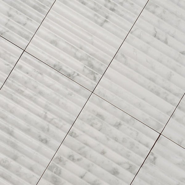 Wandfliesen in Marmoroptik mit geriffelter Struktur in quadratischer Anordnung.