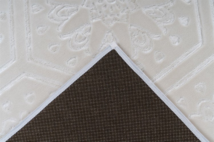 Nahaufnahme eines Teppichs mit geprägtem Ornamentmuster und rutschhemmender Rückseite mit kleinen Punkten.