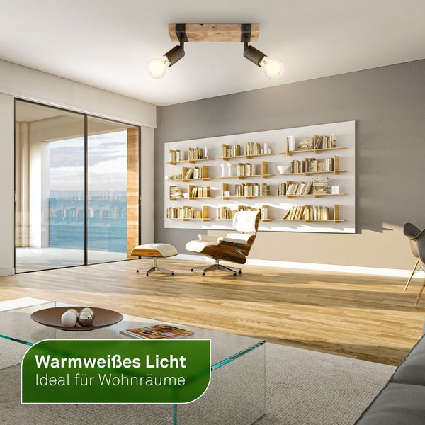 Zweiflammige Deckenleuchte aus Holz und Metall im modernen, hellen Wohnzimmer mit Parkettboden und Designersessel. Warmweißes Licht.