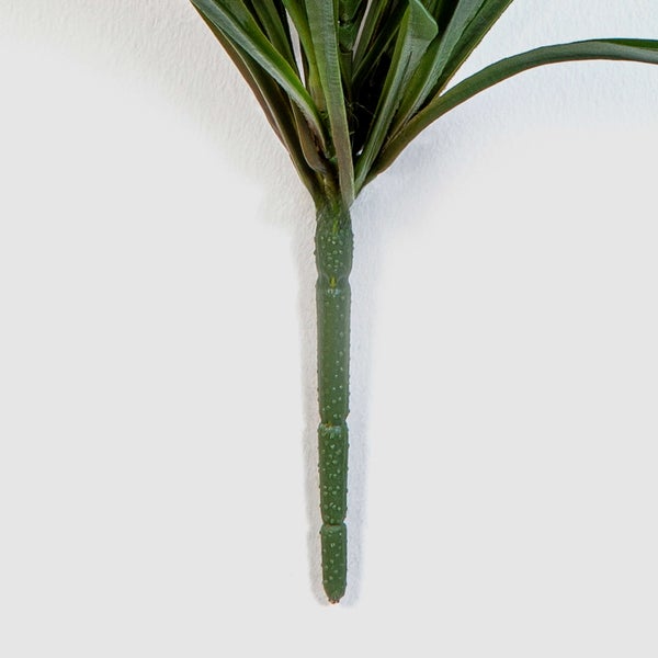 Nahaufnahme eines grünen künstlichen Pflanzenstiels mit strukturierter Oberfläche und schmalen Blättern.