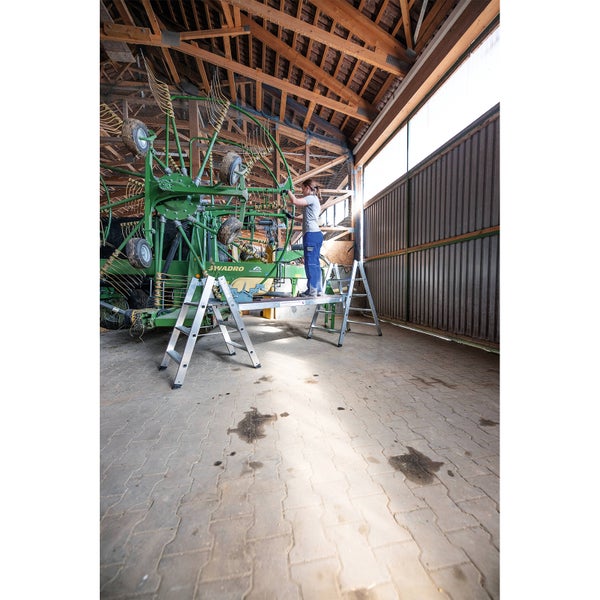 Aluminium Arbeitsbühne mit stehender Person in einer Lagerhalle.