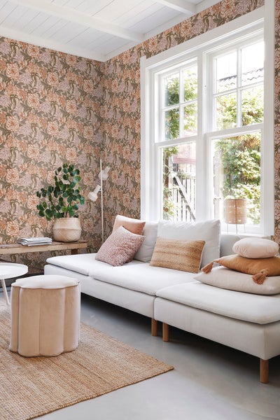 Wohnzimmer mit floraler Tapete, weißem Sofa und Holztisch