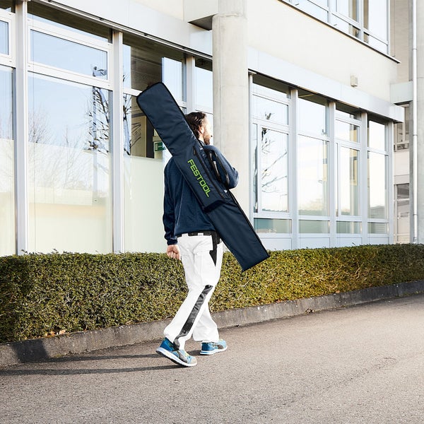Hand fixiert eine Führungsschiene mit einem Klettverschlussgurt in einer gepolsterten Tasche.