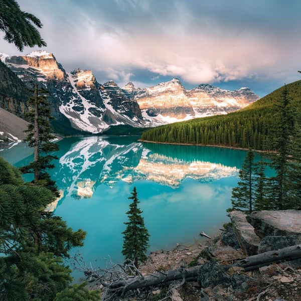 Bergsee umgeben von schneebedeckten Bergen und Nadelbäumen