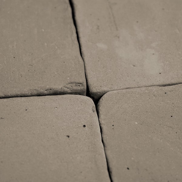Nahaufnahme von quadratischen Pflastersteinen aus Beton mit abgerundeten Kanten in einem Verlegeverband.