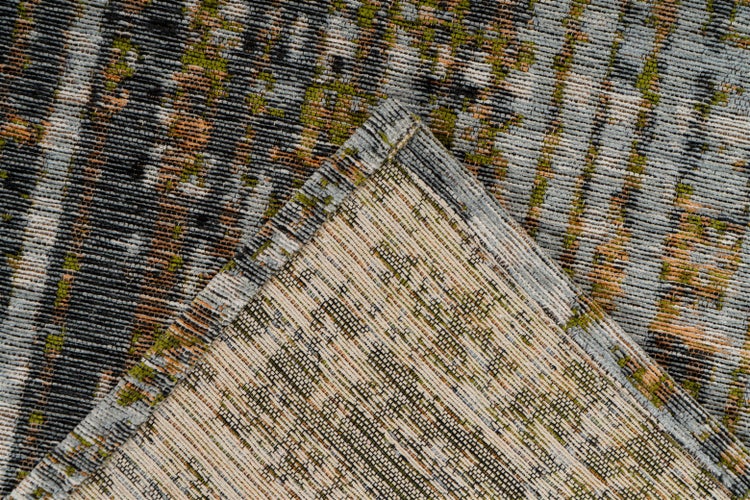 Nahaufnahme eines gewebten Teppichs mit gestreiftem Muster und umgeknickter Ecke zur Ansicht der Rückseite.