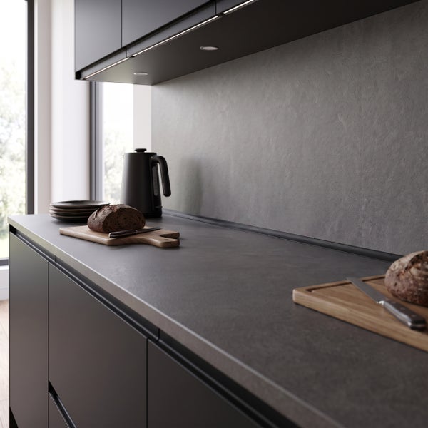 Moderne Küche mit dunkler Arbeitsplatte und Rückwand in Steinoptik, ergänzt durch Holzschneidebretter und Wasserkocher.
