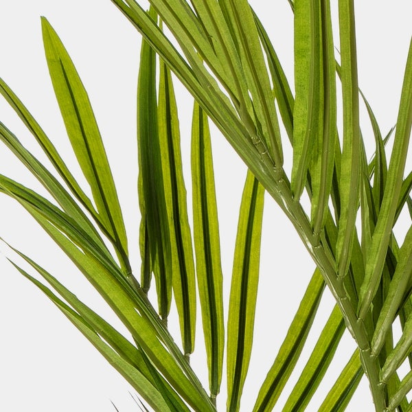 Nahaufnahme der Basis einer künstlichen Palme mit faserigen Stämmen in einem schwarzen Topf.