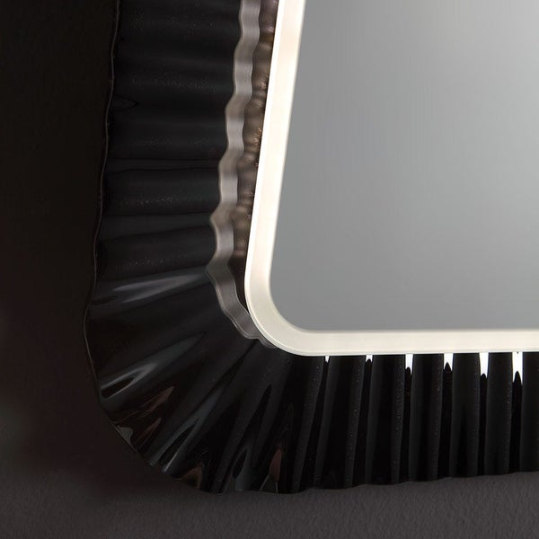 Nahaufnahme einer Spiegelecke mit schwarzem, plissiertem Dekorrahmen und beleuchtetem Innenrand.