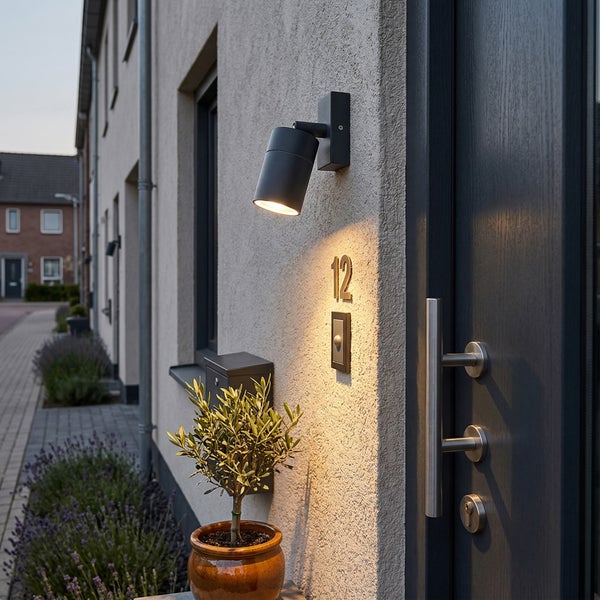 Moderne Außenwandleuchte an einer Hausfassade neben dem Eingang mit Hausnummer und Klingel.