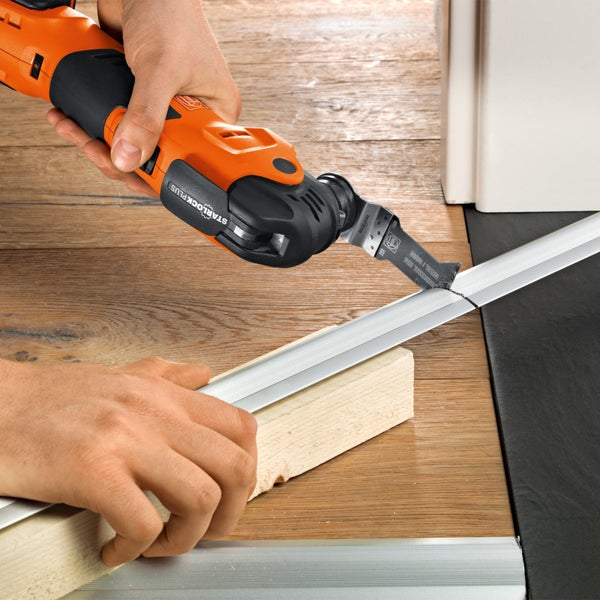 Oszillierendes Elektrowerkzeug beim Kürzen einer Metallschiene auf einem Holzboden