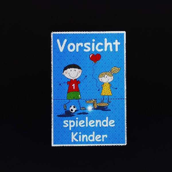 Schild mit der Aufschrift 'Vorsicht spielende Kinder' und Kinderabbildungen
