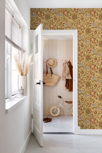 Hell gestalteter Flur mit floral gemusterter Vliestapete an der Wand neben einer offenen weißen Tür zu einem Garderobenbereich.