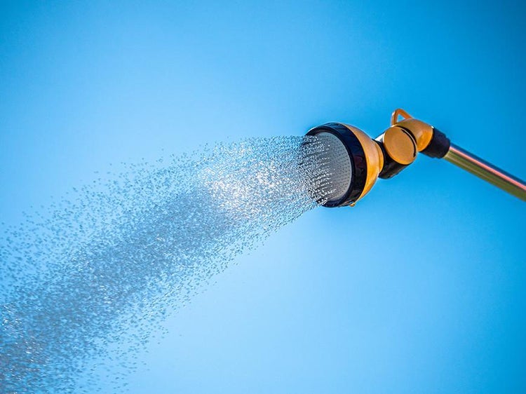 Wohnraum mit geometrischer Tapete, Bank, Kissen, Decke und Stehlampe