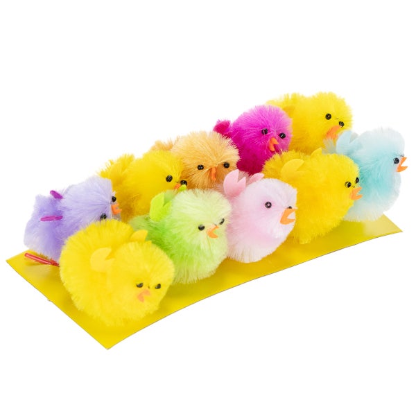 Bunte flauschige Deko-Küken für Ostern auf gelber Unterlage.