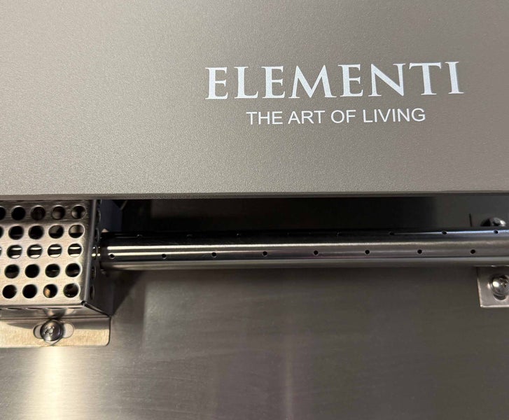 Elementi Logo auf einem Bauteil mit einem Brennerrohr aus Edelstahl und einem Zündgehäuse.