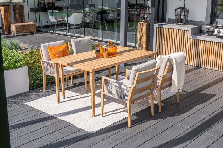 Gartenmöbel-Set aus Holz mit rechteckigem Tisch und vier Sesseln mit Seilbespannung und Kissen auf einer modernen Terrasse.