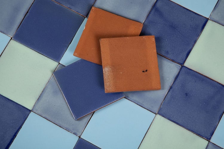 Quadratische Bodenfliesen in verschiedenen Blautönen und Terrakotta