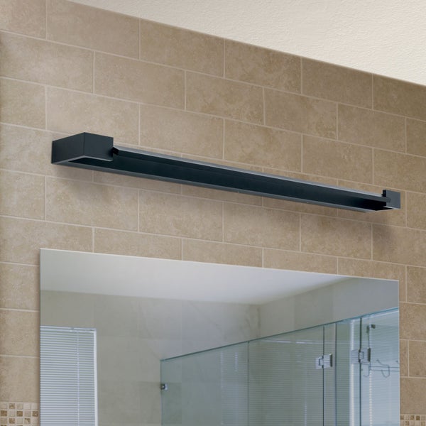 Moderne längliche LED Spiegelleuchte in minimalistischem Design montiert über einem Badezimmerspiegel vor einer hellen Fliesenwand.