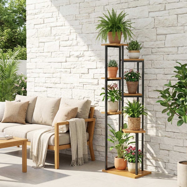 Mehrstöckiges Pflanzregal mit schwarzem Metallgestell und Holzböden auf einer hellen Terrasse neben einem Holzsofa.