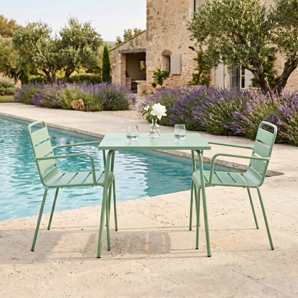 Quadratischer Bistro-Tisch für den Außenbereich mit zwei passenden Metallstühlen mit Lattenrost an einem Pool in einem Garten mit Lavendel.