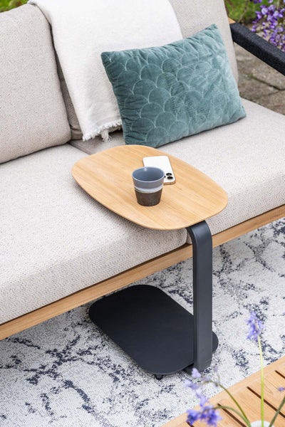 Ovaler Beistelltisch mit Holzplatte und Metallgestell an einem Sofa mit Kissen und einer Decke auf einem Teppich.