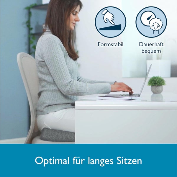 Frau sitzt mit Sitzkissen auf Stuhl und arbeitet am Laptop