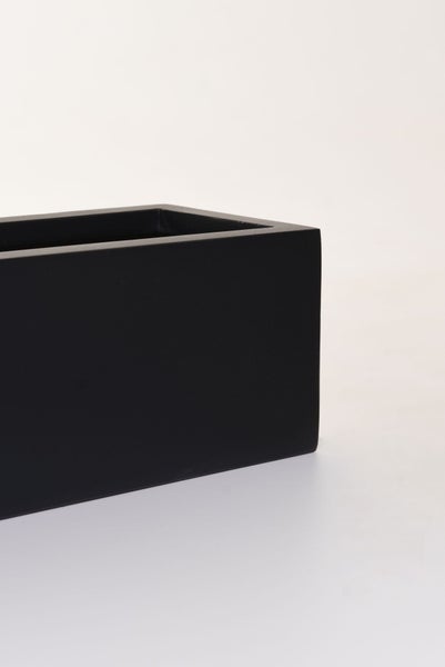Detailansicht eines rechteckigen, schwarzen Pflanzkübels mit matter Oberfläche.