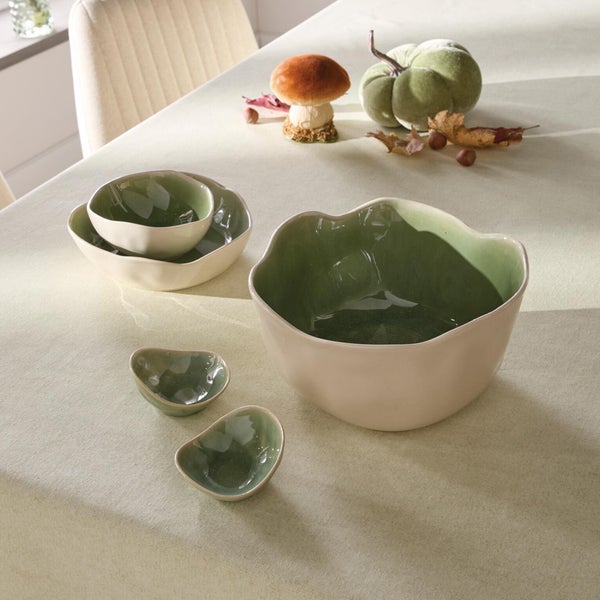 Set aus vier Keramikschalen mit geschwungenen Rändern in organischer Form auf einem gedeckten Tisch mit herbstlicher Dekoration.