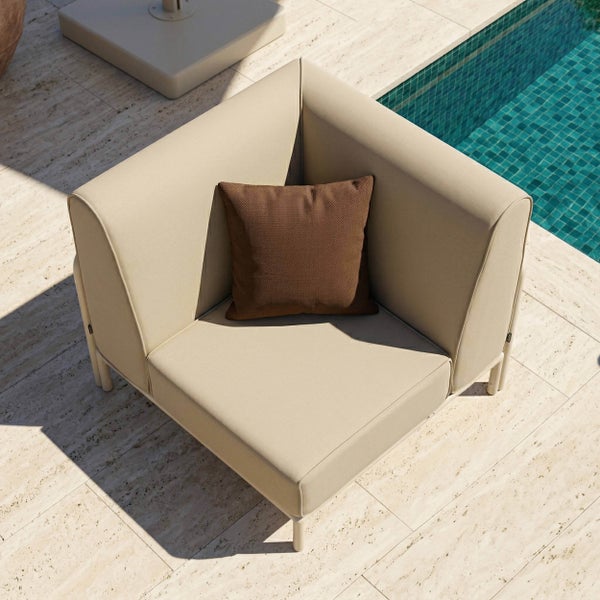 Outdoor-Lounge-Eckelement mit Polsterung und braunem Zierkissen auf einer hellen Steinterrasse am Swimmingpool.
