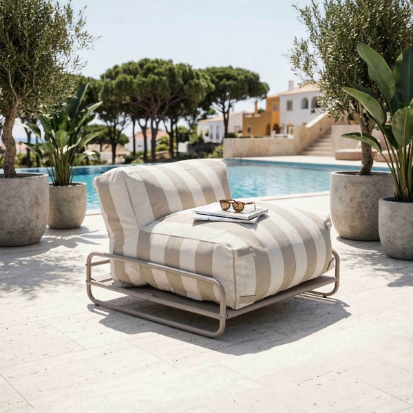 Gestreifter Outdoor-Loungesessel mit Metallrahmen auf einer hellen Terrasse neben einem Pool, umgeben von großen Pflanzkübeln und Bäumen.