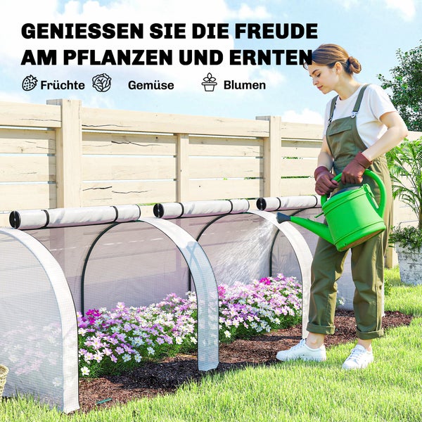 Eine Frau gießt Blumen in einem kleinen Folientunnel im Garten mit einer Gießkanne.