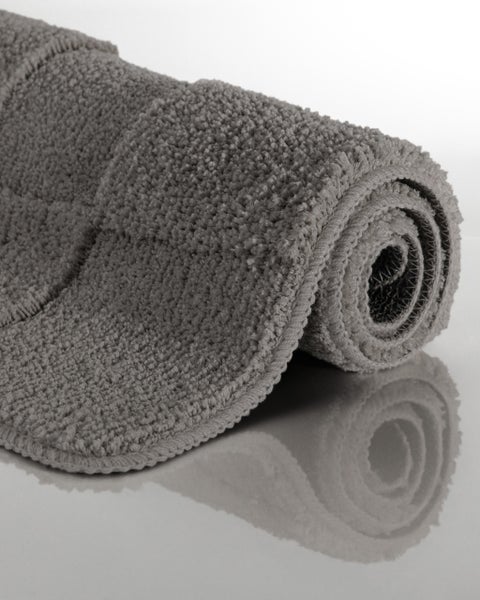 Badematte grau, aufgerollt, weiche Textur mit hohem Flor.