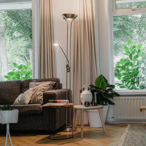 Wohnzimmer mit Sofa, Beistelltischen, Zimmerpflanzen und Stehlampe