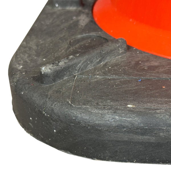 Zwei rot-weisse Verkehrskegel mit reflektierenden Streifen auf einer schwarzen Basis vor einer Steinmauer