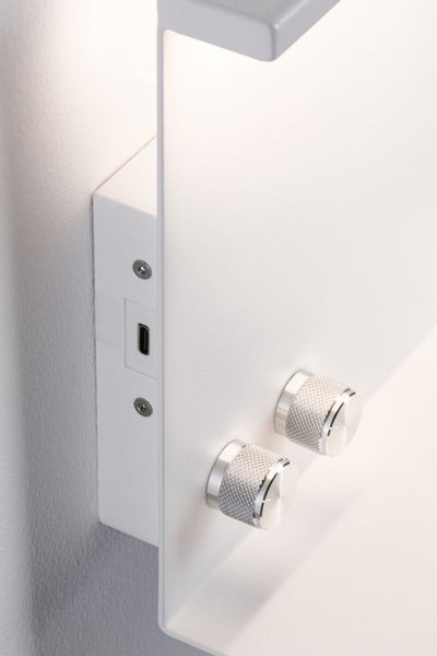 Detailansicht einer weißen Wandleuchte mit integriertem USB-Anschluss an der Seite und zwei gerändelten Drehreglern an der Vorderseite.