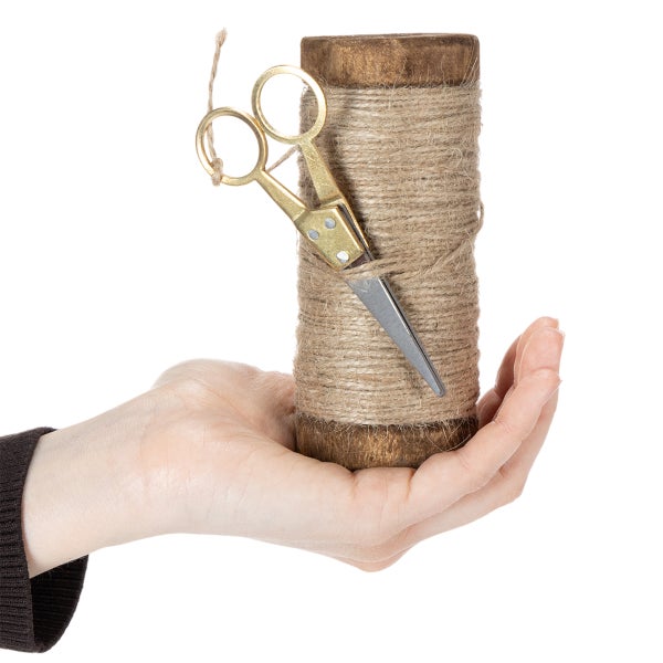 Holzspule mit Jutekordel und kleiner Schere in einer Hand gehalten.