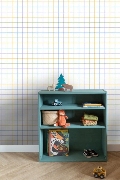 Helles Kinderzimmer mit weißer Tapete mit buntem handgezeichnetem Karomuster und einem blaugrünen Regal mit Spielzeug und Büchern.