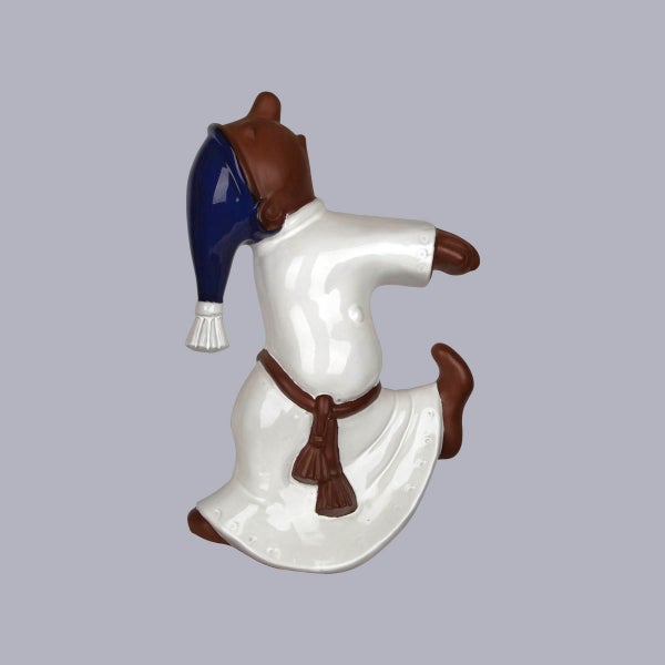Dekorative Wandfigur aus Keramik, tanzende Figur in weißem Gewand mit blauem Hut.