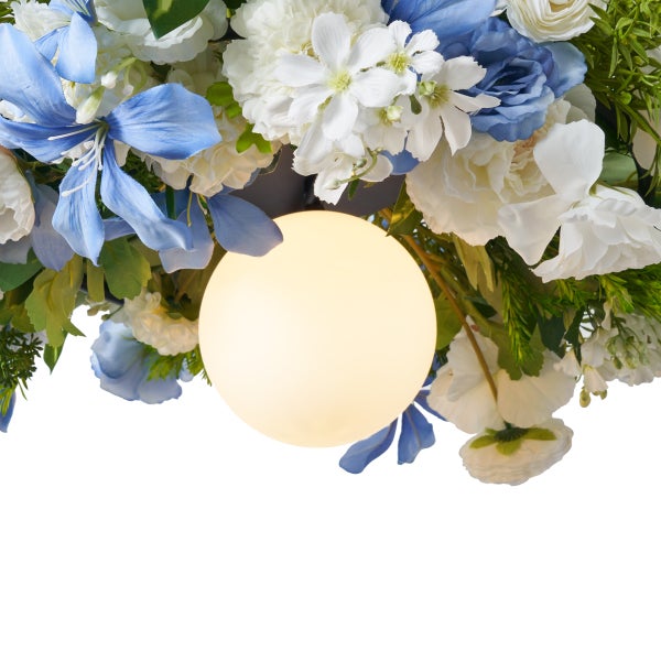 Nahaufnahme einer Deckenleuchte mit einem runden, leuchtenden Leuchtmittel, umgeben von blauen und weissen Kunstblumen.