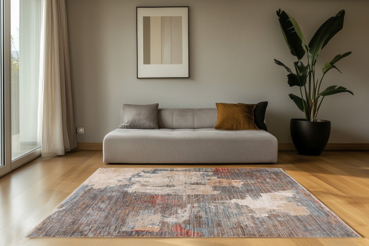 Modernes Wohnzimmer mit flachem Sofa, gemustertem Teppich auf Parkettboden und einer Topfpflanze vor einer Wand mit gerahmtem Bild.